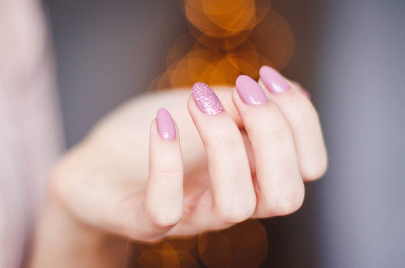 Mano con uñas largas pintadas de color rosa.