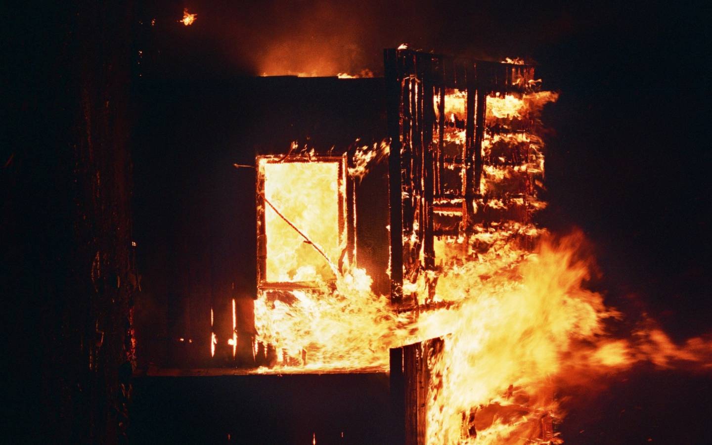 Una casa en llamas, completamente destruída. Foto nocturna.