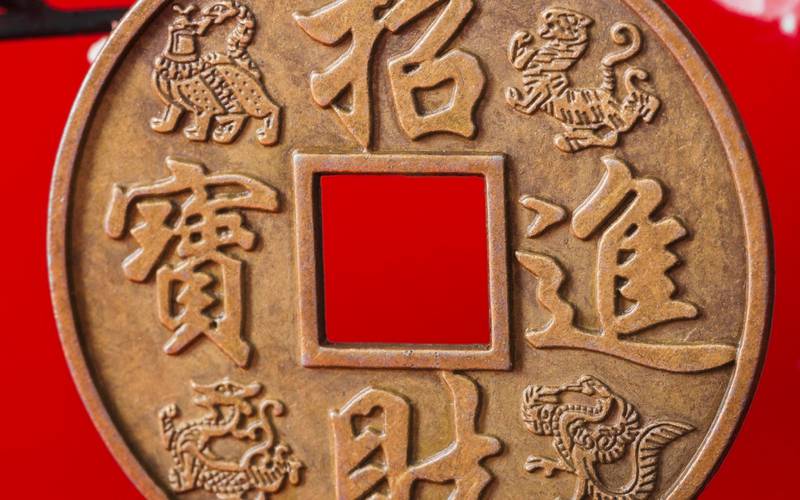 Sobre un fondo rojo se aprencia el primer plano de una moneda china