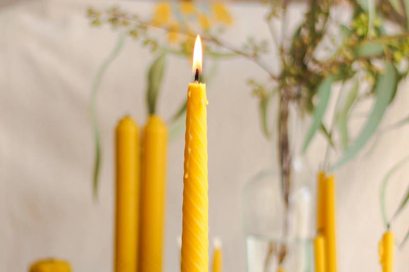 Primer plano de una vela amarilla, cuya llama está encendida.