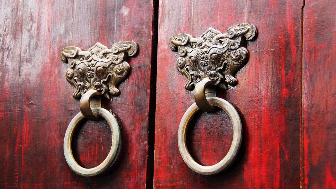 Imagen de una puerta burdeo con manijas forjadas en bronce en forma de dragón