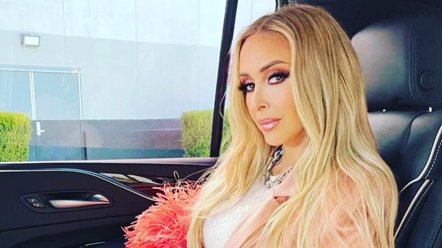 Mujer en medio plano miirando de medio perfil a la cámara en un auto lujoso.