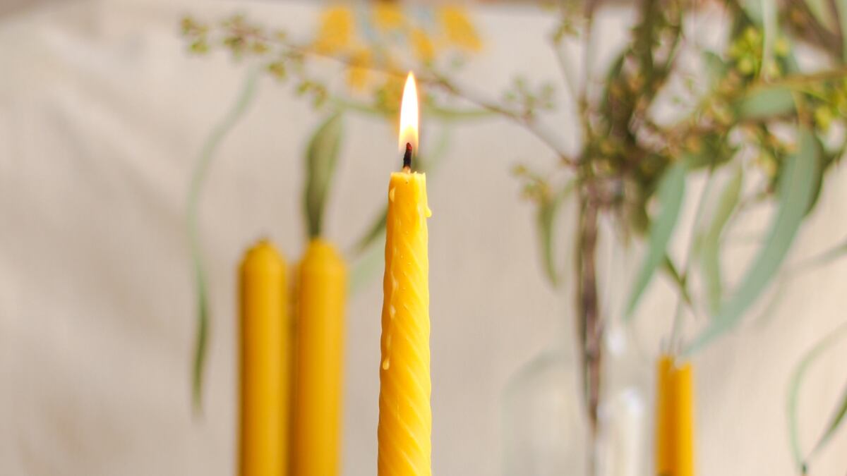 Primer plano de una vela amarilla, cuya llama está encendida.