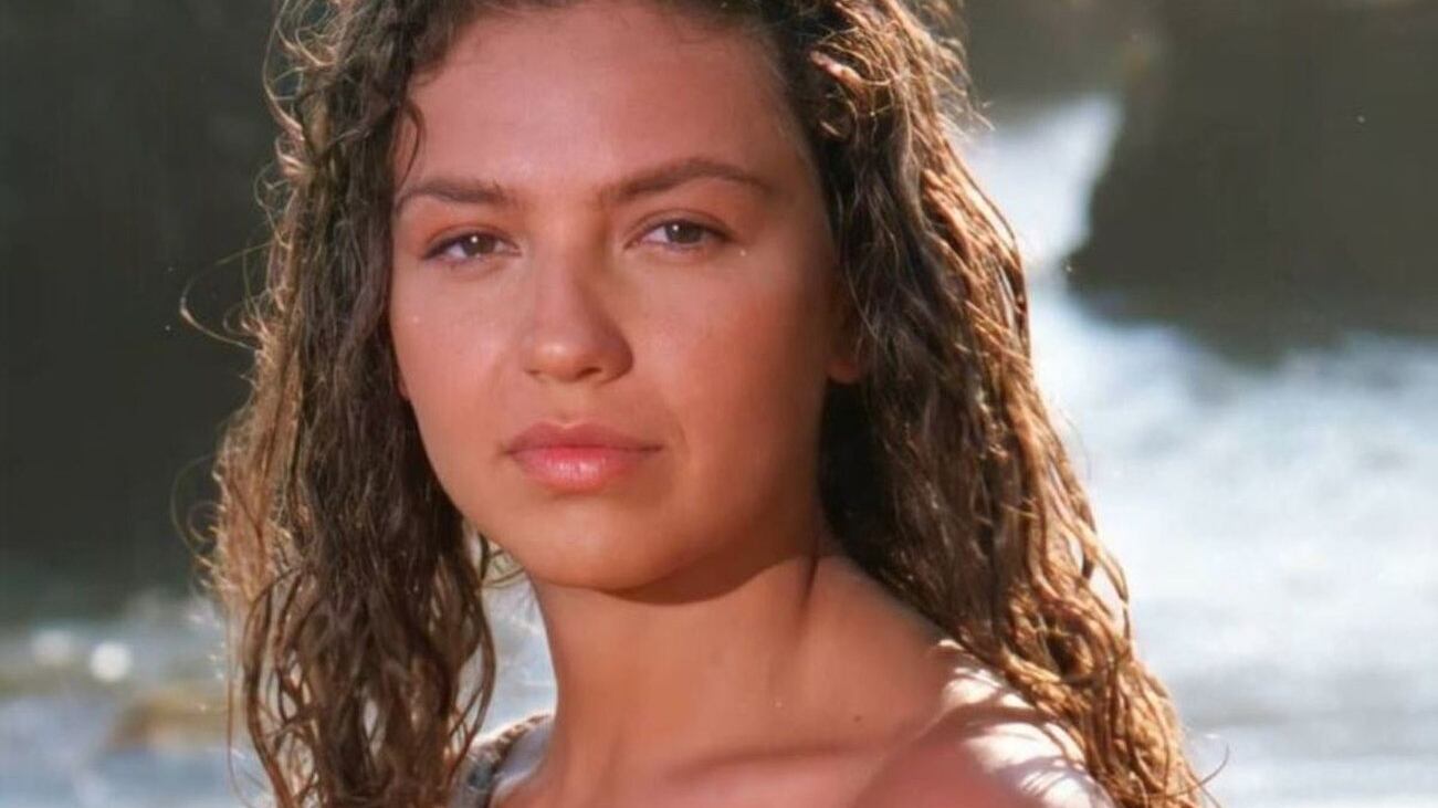 Primer plano de la cara de Thalía en Marimar, con el pelo mojado y sin maquillaje con el mar de fondo.
