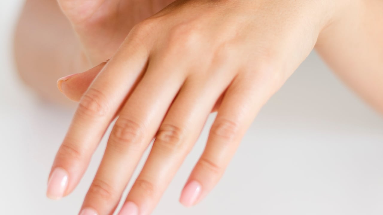 Primer plano de un par de manos femeninas, con uñas pintadas de color rosa.