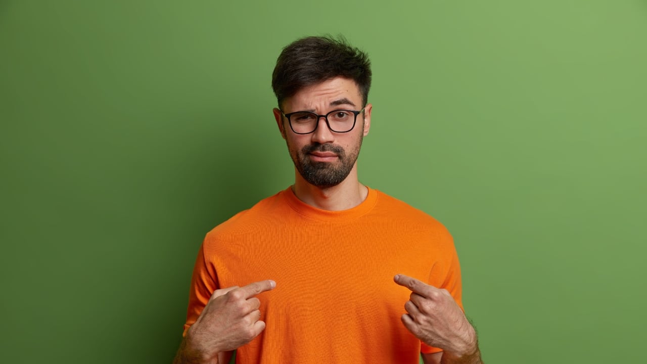 Un hombre joven apuntándose a si mismo.