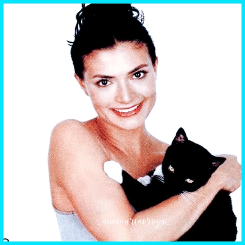 Ana maría orozco posa sonrriendo a la cámara con un gato negro con pintas blancas en los brazos