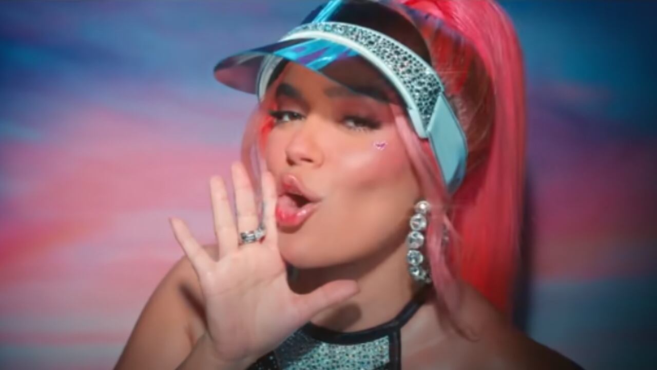 Karol G cantando en el video de Watati. Tiene una mano cerca de la boca, amplificando lo que está cantando.