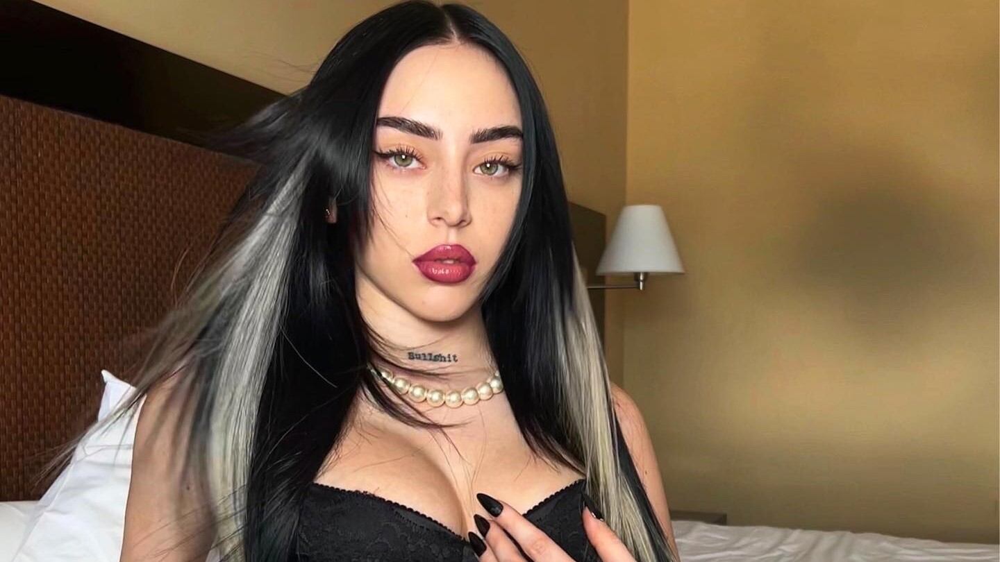 Mujer de frente mirando a la cámara en brassier negro, en una habitación de hotel