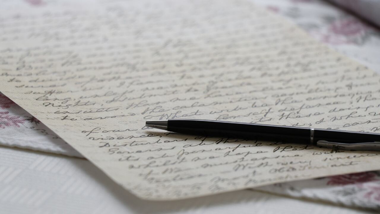 Papel escrito a mano, con un lápiz encima.