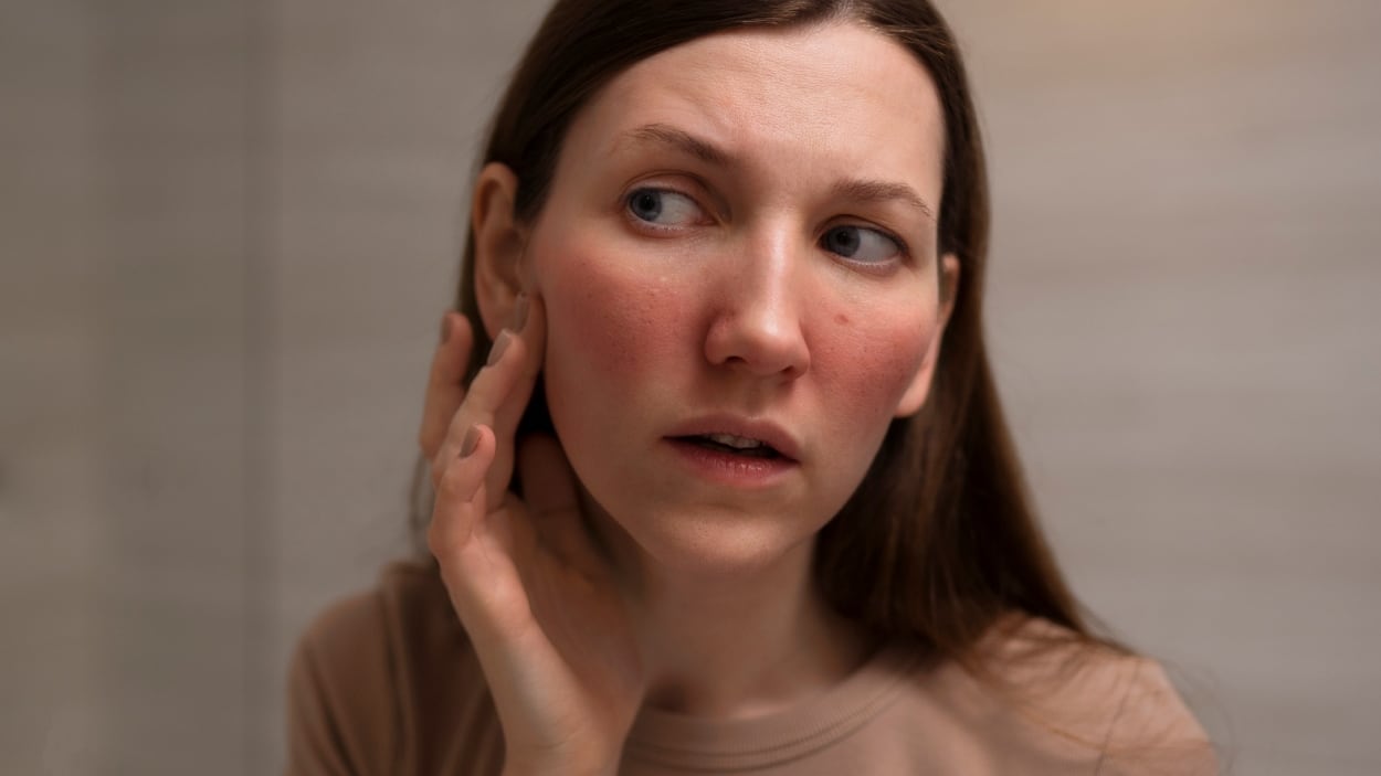 Una mujer joven tocándose la cara.