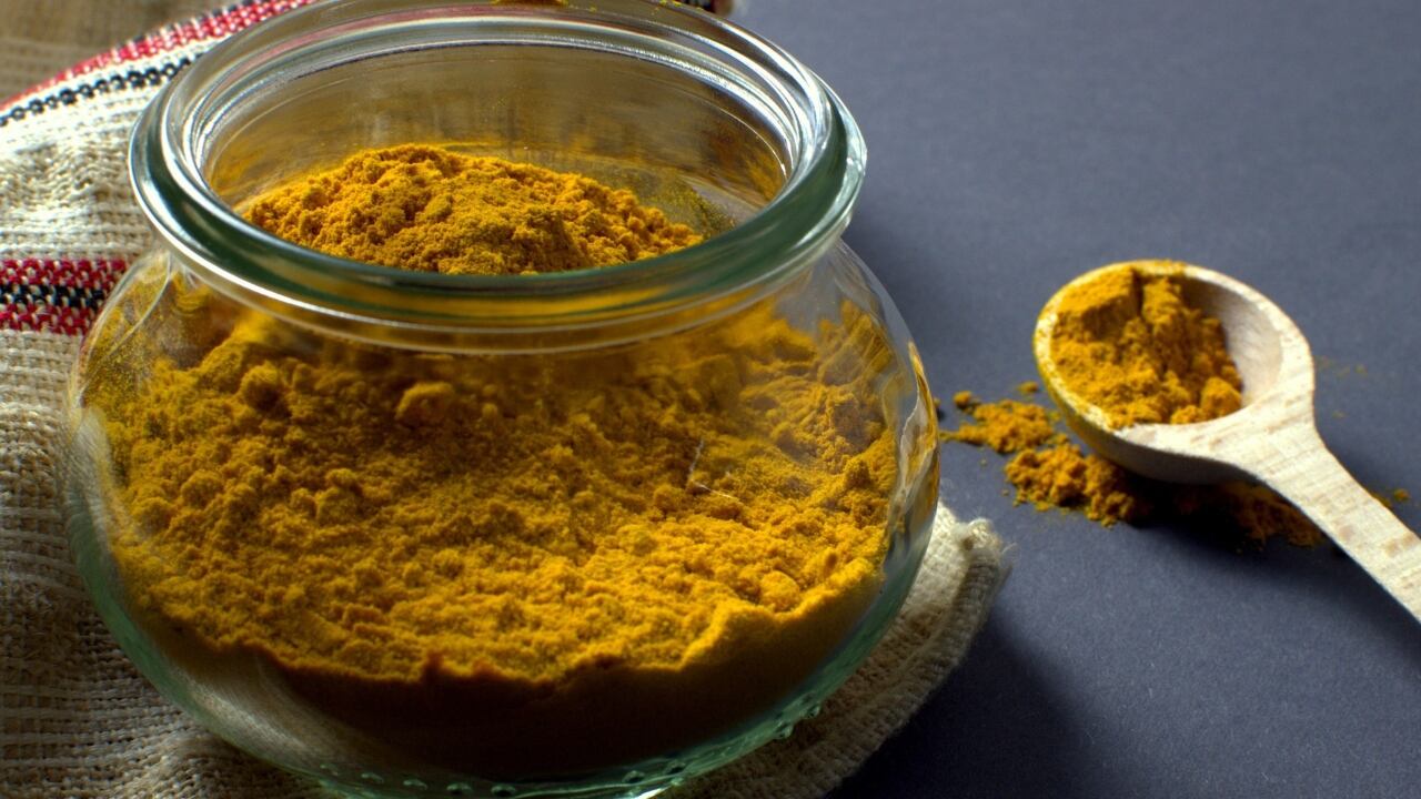 Pote de vídrio con cúrcuma en polvo.