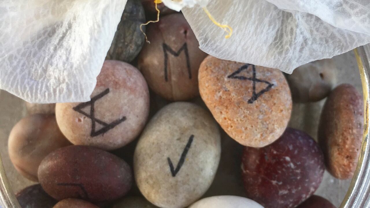 Frasco con runas pintadas en piedras de colores diversos